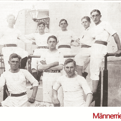 Schwarz-weiß Foto von acht Männern in Sportkleidung, posierend an einem Reck, datiert auf 1912.