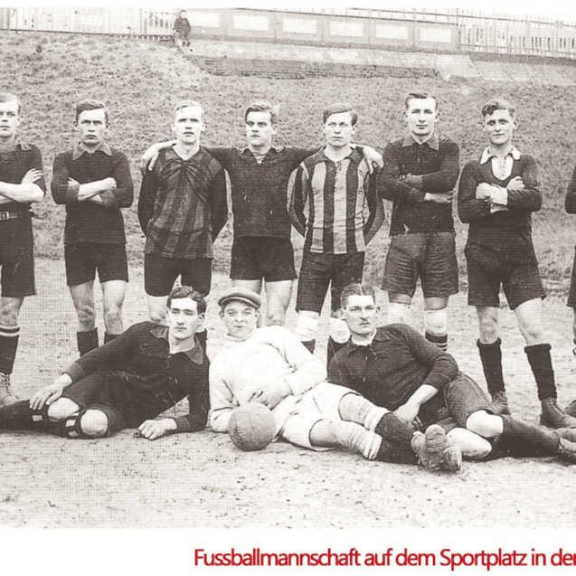 Historisches Gruppenfoto einer Fußballmannschaft auf einem Sportplatz, gekleidet in schwarz-weiße Trikots.
