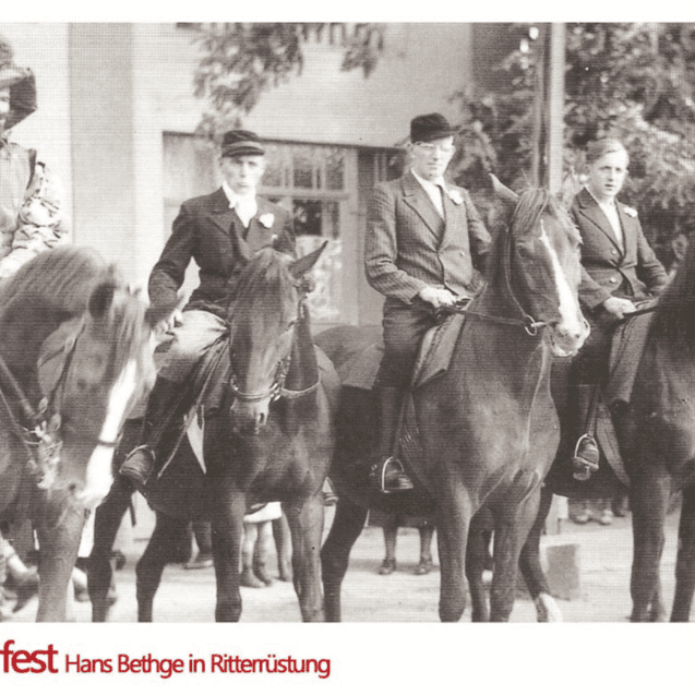 Reiterfest mit mehreren Menschen in historischen Kostümen auf Pferden vor einem Gebäude.