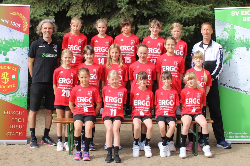 Mannschaftsfoto der Jugendmannschaft von SV Eiche 05 Biedert mit Trainern, in roten Trikots auf einem Sportplatz.
