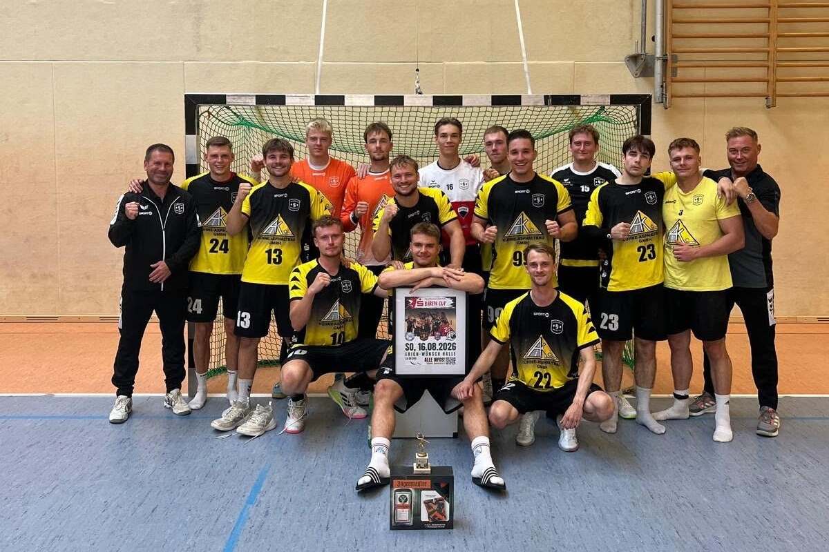 Mannschaftsbild einer Handballmannschaft in gelb-schwarzen Trikots mit Pokal und Urkunde in der Sporthalle.