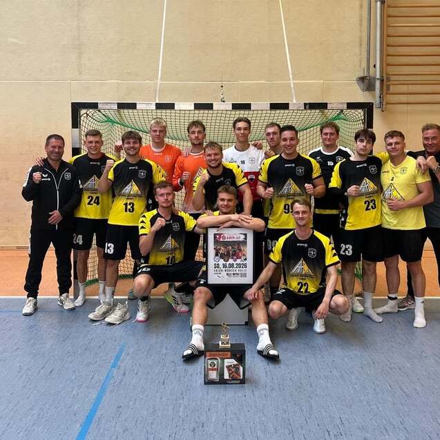 Mannschaftsbild einer Handballmannschaft in gelb-schwarzen Trikots mit Pokal und Urkunde in der Sporthalle.