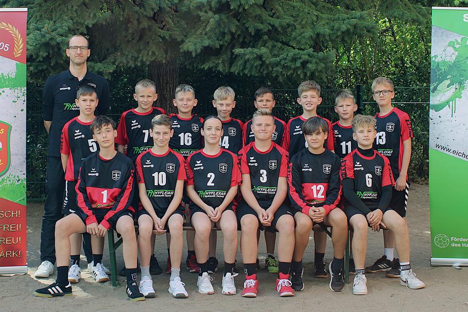 Gruppenshot einer Basketballmannschaft mit Trainer, im Hintergrund zwei Banner des Vereins SV Eiche 05 Biedertitz.