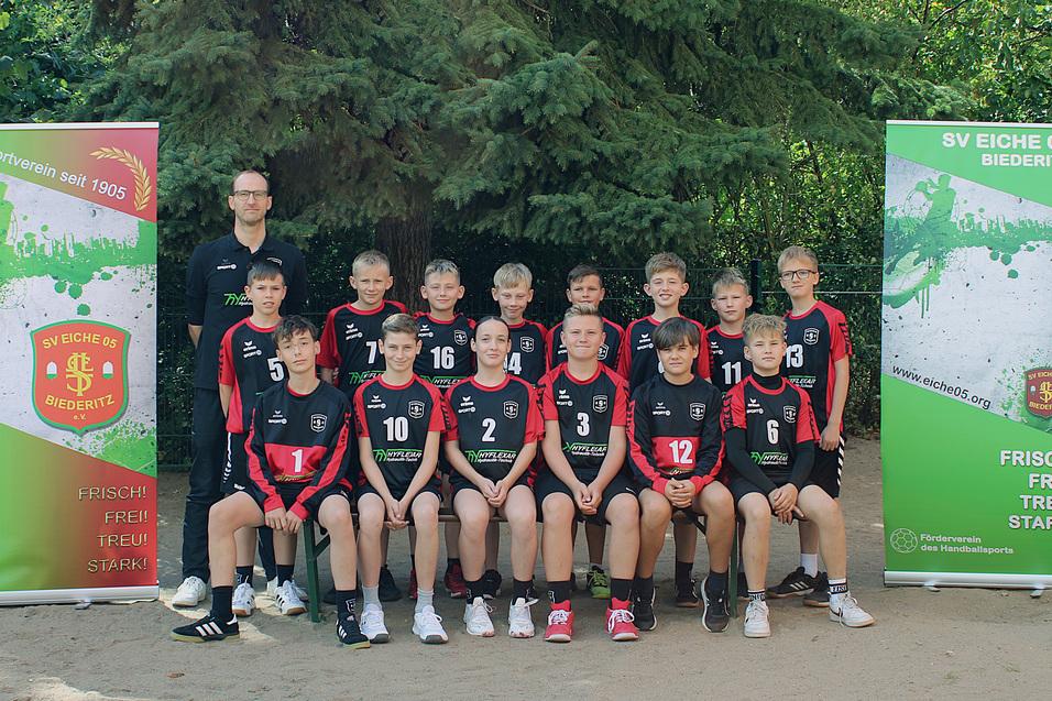 Gruppenshot einer Basketballmannschaft mit Trainer, im Hintergrund zwei Banner des Vereins SV Eiche 05 Biedertitz.
