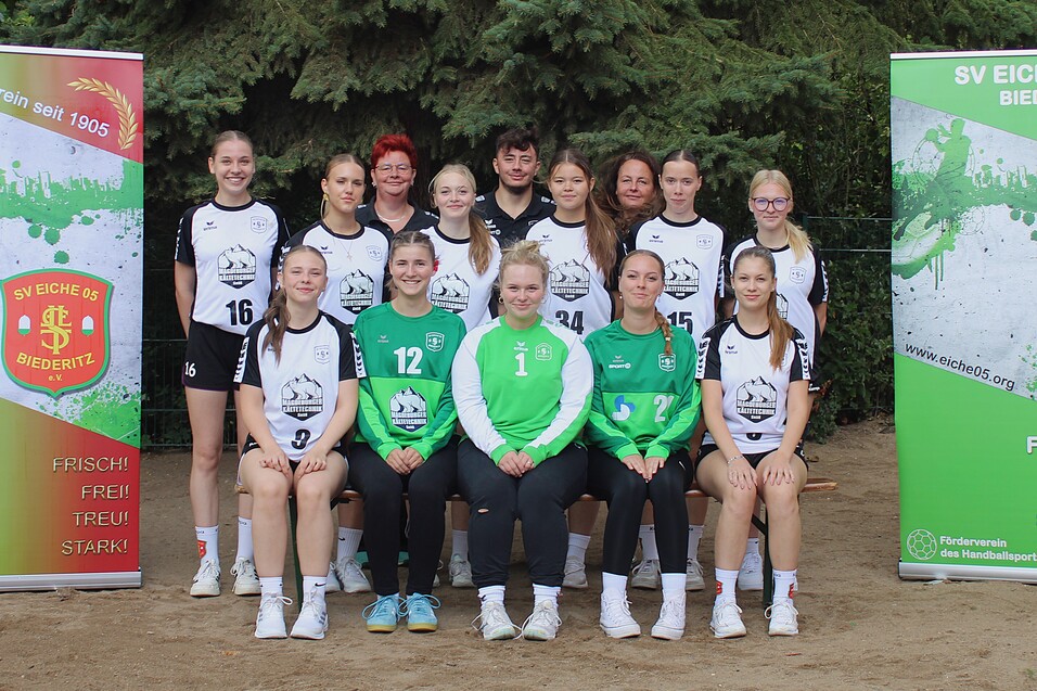 Gruppenfoto des Frauenhandballteams von SV Eiche 05 Biedertz, mit Vereinsbanner im Hintergrund, auf einem Sportplatz.