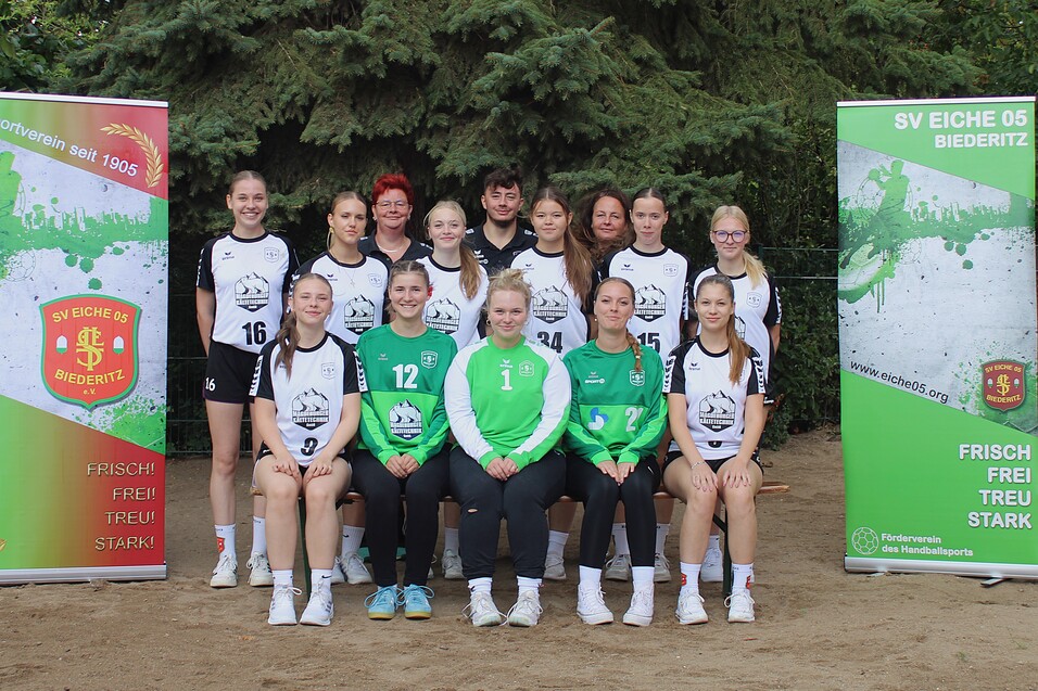 Gruppenfoto des Frauenhandballteams von SV Eiche 05 Biedertz, mit Vereinsbanner im Hintergrund, auf einem Sportplatz.
