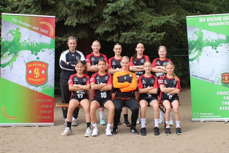 Mannschaftsphoto von 10 Frauen im Sportoutfit, stehend und sitzend vor zwei Vereinsbanner des SV Eiche 05 Biederitz.