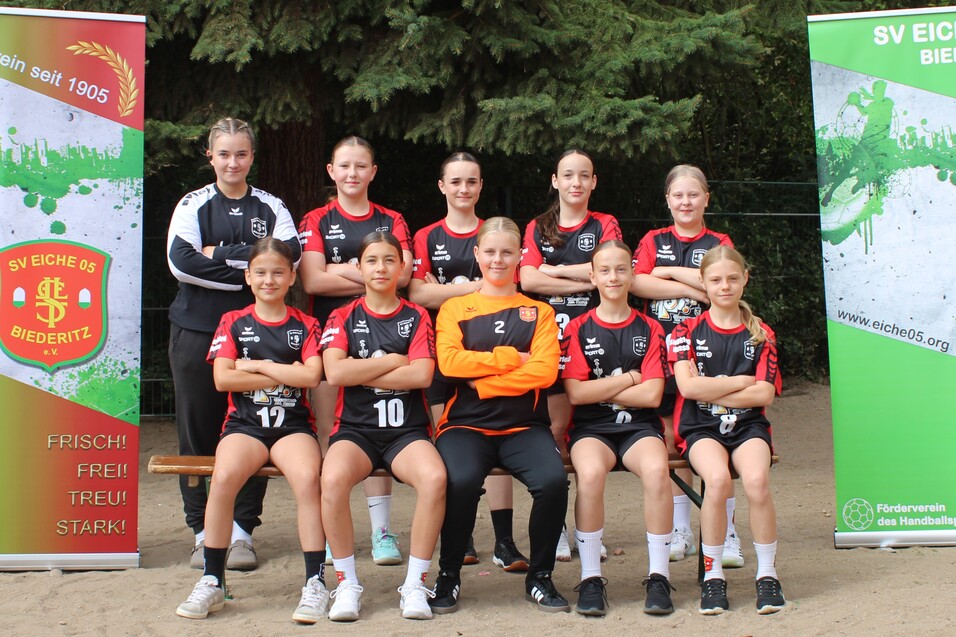 Mannschaftsphoto von 10 Frauen im Sportoutfit, stehend und sitzend vor zwei Vereinsbanner des SV Eiche 05 Biederitz.