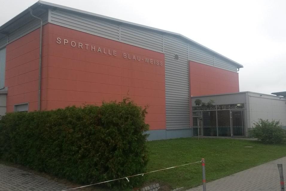 Au&szlig;enansicht der Sporthalle Blau-Wei&szlig; mit orangefarbener Fassade und umliegendem Gr&uuml;nbereich.